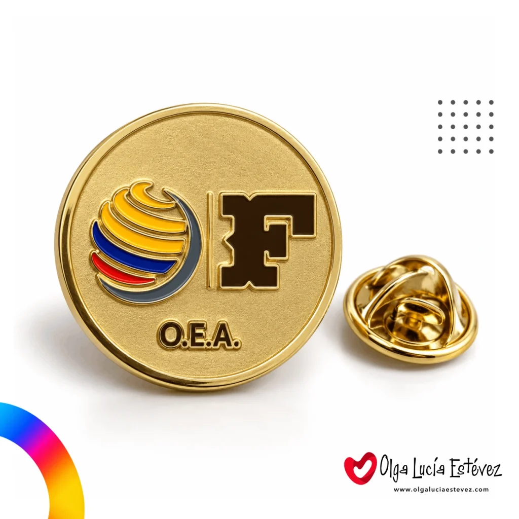 Pin metálico fotograbado en acabado dorado brillante con logo institucional O.E.A. y cierre de mariposa.